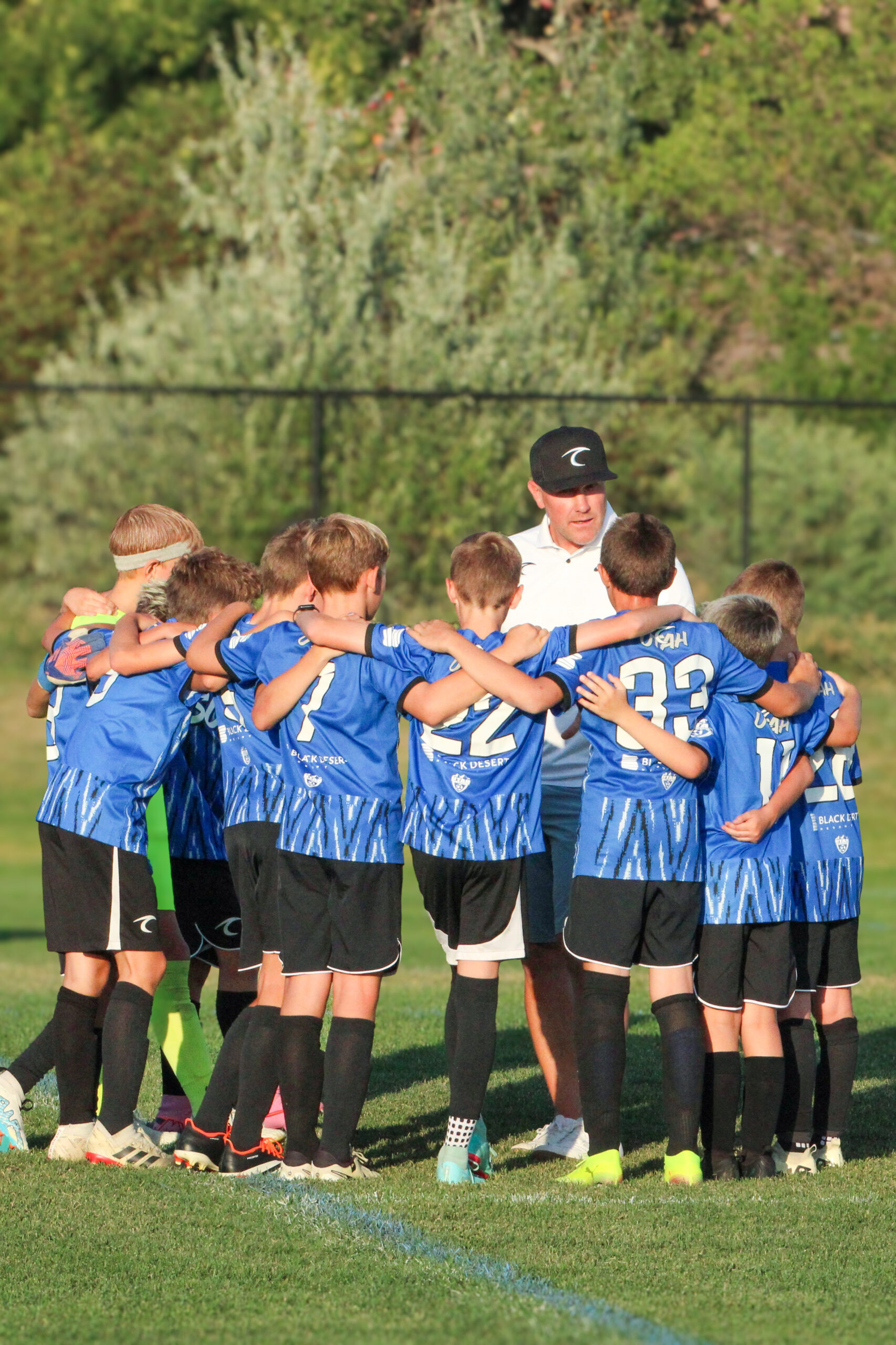 A Utah Surf boys team in a huddle with their coach