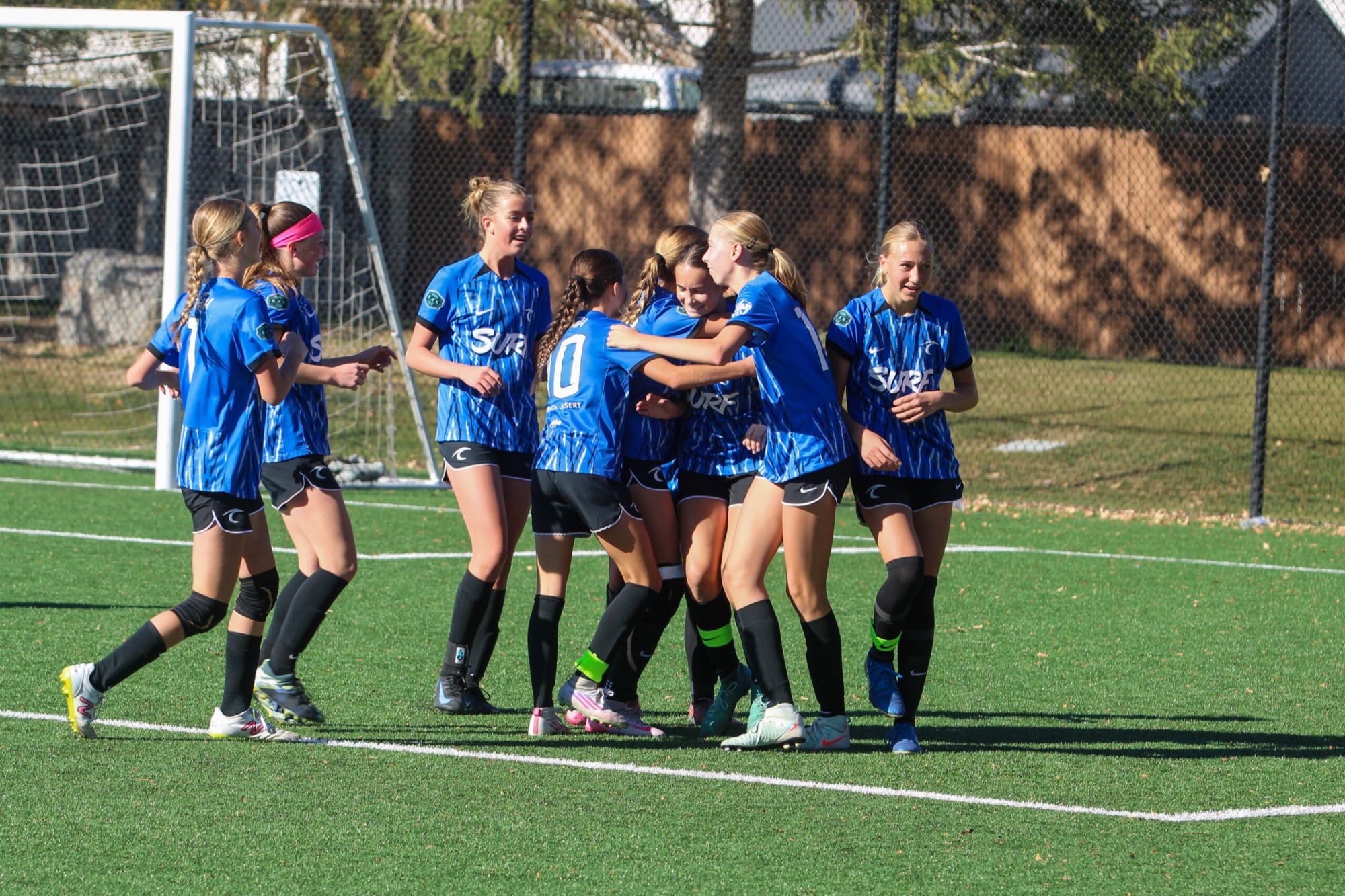 Utah Surf girls in blue kits celebrating a goal together