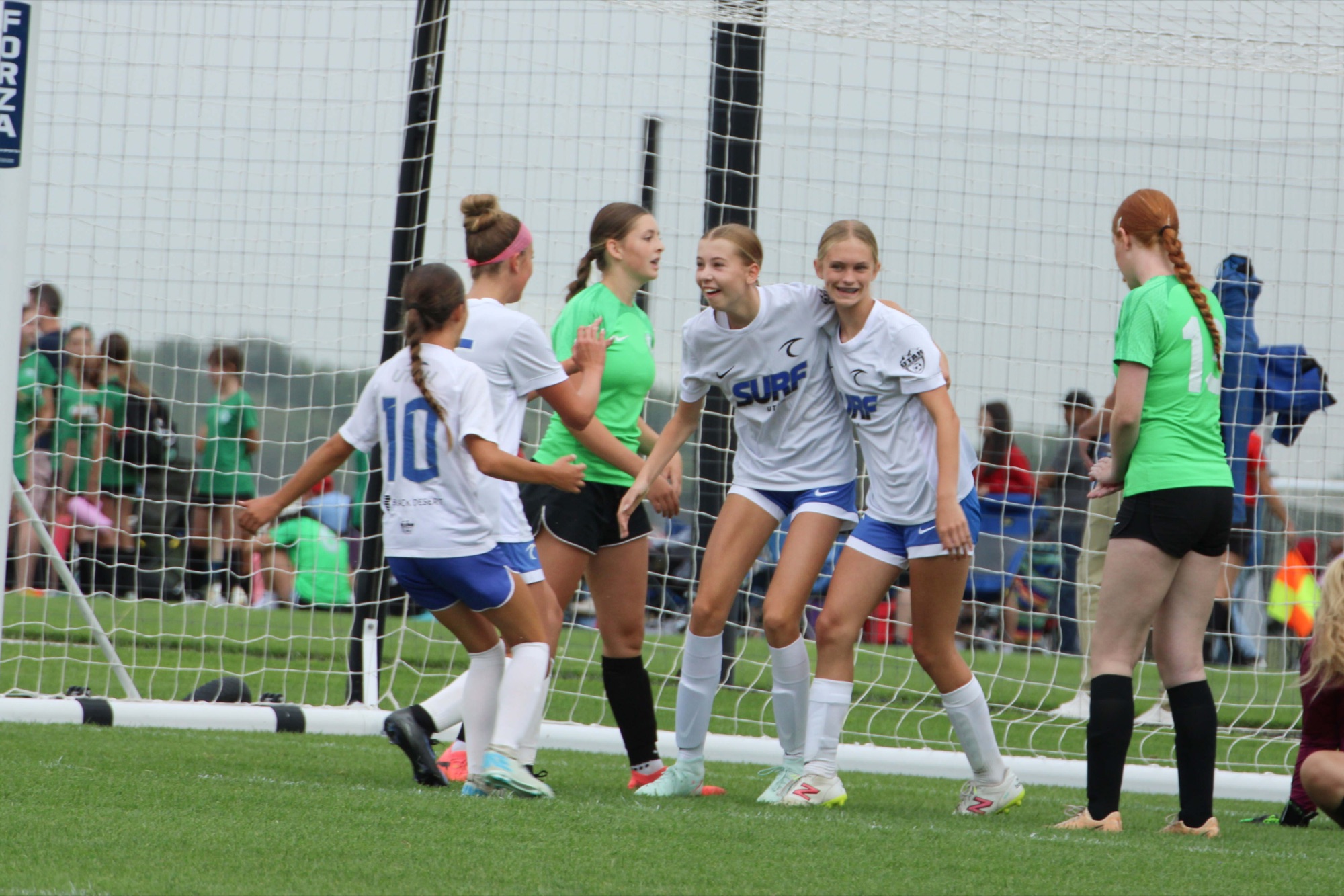 Utah Surf girls in white kits hugging after a goal
